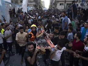 Palestinians carry an injured person on a stretcher after an airstrike in Khan Younis, Gaza Strip, Saturday, Oct. 21, 2023.