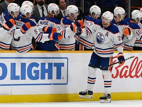 Leon Draisaitl skates past the Oilers bench bumping fists with teammates after scoring a goal