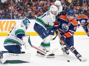 Vancouver Canucks' goalie Casey DeSmith (29) makes the save as Akito Hirose (41) and Edmonton Oilers' Connor McDavid (97) battle for the puck during second period NHL action in Edmonton on Saturday, Oct. 14, 2023.