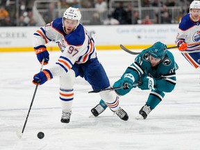Connor McDavid #97 of the Edmonton Oilers skates with the puck pursued by Luke Kunin #11 of the San Jose Sharks during the first period at SAP Center on November 09, 2023 in San Jose, California.