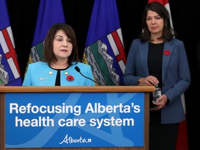 Health Minister Adriana LaGrange atands at a podium with the words "Refocusing Alberta's health care system" as Premier Danielle Smith stands in the background infront of Canadian and Alberta flags during the unveiling of provincial health-care reform plans