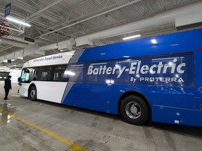 An ETS electric bus with the words "Battery-Electric By Proterra" painted on its side in an ETS bus garage