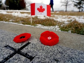 Poppies and a mini Canadian flag on a granite grave marker.