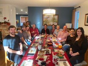 A group of people sit around a large dining table set for a festive afternoon meal