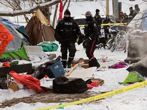 Police officers survey tents in an encampment