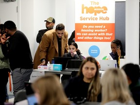 People mill about a room equipped with tables to process homeless people, with a Hope Mission banner in the background