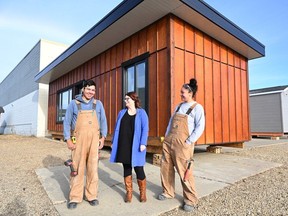 Residential construction program student Jessie Johnson, left, poses for a photo with Shannon McCarthy, executive director of Trade Winds to Success, and student Mae Steinhauer outside a completed mini home at the Trade Winds to Success workshop in Edmonton.
