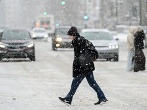 A person crosses a street as snow falls in Montreal, Sunday, January 7, 2024.