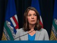DAnielle Smith at a podium against a backdrop of Alberta flags