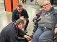 Two men work on the wheel of Cam's wheelchair