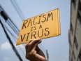 A man holding Racism is a Virus sign