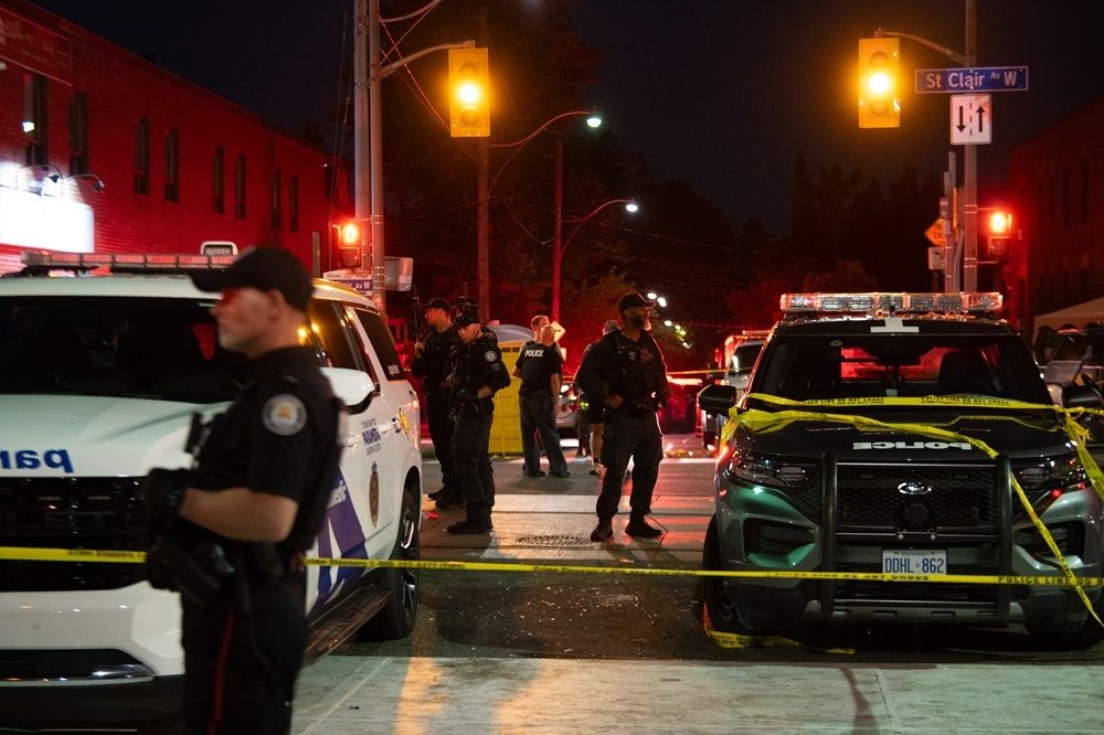 Police officers and other law enforcement personnel are seen at the intersection of St. Clair W. and Arlington Ave., near the site of a shooting that occurred at the Salsa on St. Clair Festival in Toronto on the evening of July 11, 2026.