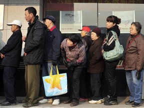Residents wait in a queue outside a branch of the Industrial and Commercial Bank of China. China's latest interest rate rise will help draw more money into bank deposits and deter property speculation, according to Li Daokui, an academic adviser to the People's Bank of China.