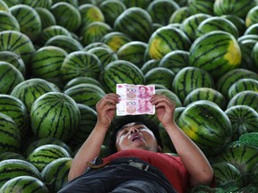 A watermelon vendor looks at yuan banknotes at a market. Benjamin Tal, deputy chief economist with CIBC World Markets, said the debt-to-GDP ratio for China may be north of 50%.