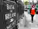 A pedestrian passes a Bank of Ireland automated sign outside a branch in Dublin, Ireland.