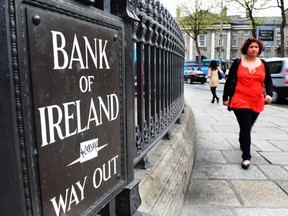 A pedestrian passes a Bank of Ireland automated sign outside a branch in Dublin, Ireland.