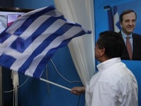 A conservative New Democracy supporter waves a Greek flag by a television screen showing exit polls in the main New Democracy campaign center in Athens' Syntagma square.