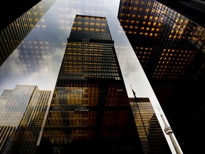 Bank towers are reflected in a window in the financial district of Toronto