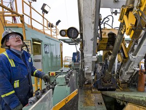 An employee operates the controls for a spinning drill on a Precision Drilling rig at an Encana natural gas well site near Alix, Alberta