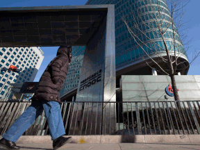 A woman walks past the headquarters of the state-owned China National Offshore Oil Corp. (CNOOC) in Beijing, China.