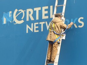 A worker paints in the letters before new signs were hung over old Nortel Networks signs at the campus located at Moodie Drive and Carling Avenue, signifying the end of an era.
