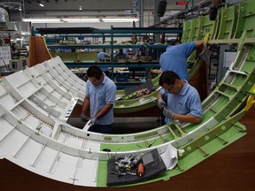 Workers build a plane in a Bombardier Aerospace plant.