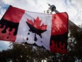 A protester holds a Canadian flag made to look like it is dripping with oil, outside the National Energy Board public hearings on the Enbridge Line 9 oil pipeline, in Toronto.