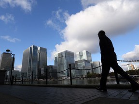 A pedestrian passes bank headquarters and commercial real estate offices in the Canary Wharf business and financial district in London, U.K.