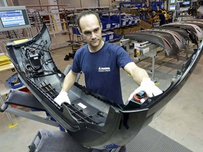 Assembler Christian Baumann carries a front car bumper in a plant of the international automotive supplier Magna in Meerane, eastern Germany