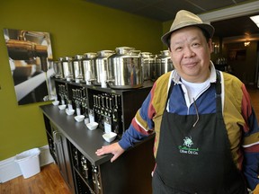 Alex Yuen poses with imported Italian Fustis containing a large assortment of extra virgin olive oil from an imported Fusti at The Collingwood Olive Oil Company in Collingwood, Ont., October 9, 2014.  Alex and his wife Cheryl McMenemy moved back to Collingwood from Owen Sound to open their upscale boutique in May 2014.