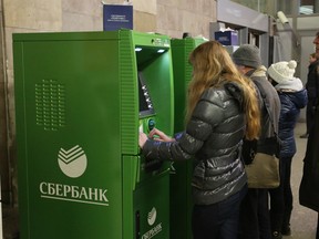 Customers queue to withdraw cash from ATMs operated by OAO Sberbank at a metro station in Saint Petersburg.