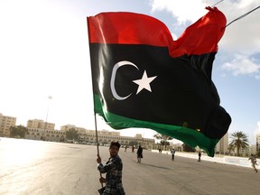 A Libyan man waves his national flag as protesters gather for a demonstration.
