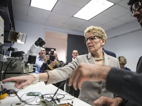 Ontario Premier Kathleen Wynne visits a lab at Ecobee, which produces Wi-Fi controlled domestic thermostats, before an announcement which outlined a cap and trade deal with Quebec aimed at curbing green house emissions, in Toronto on Monday, April 13 2015. The plan involves government-imposed limits on emissions from companies, and those that want to burn more fossil fuels can buy carbon credits from those that burn less than they are allowed. THE CANADIAN PRESS/Chris Young