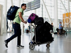 A traveler pushes a cart of luggage at Toronto Pearson International Airport in Toronto.