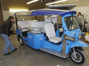 In this photo taken Friday, Feb. 27, 2015, a worker checks the roof on an electric Tuk-Tuk being prepared for export at the Denver eTuk factory in northeast Denver.