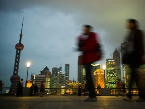 Pedestrians walk past the skyline of the city's financial district in Shanghai.