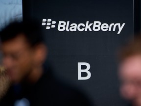 Employees walk past signage displayed at BlackBerry Ltd. headquarters in Waterloo, Ontario.