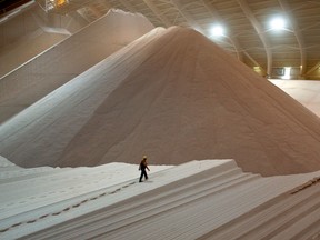An employee walks across a large mound of potash stored in a warehouse