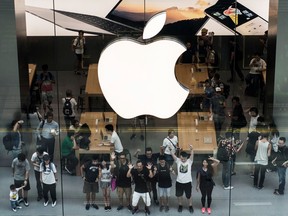 Customers pose for a photograph inside Apple Inc.'s new Canton Road store in the Tsim Sha Tsui district of Hong Kong.