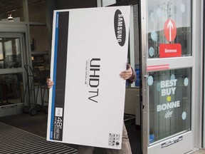 A man carries a large televison from an electronics store on Boxing Day, in Vaudreuil, Que., on Saturday, Dec. 26, 2015. Changes promising more choice in cable packages and the prospect of a cheaper bill are coming in the new year.