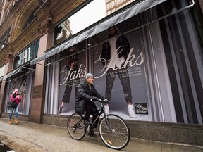A cyclist rides past the Saks Fifth Avenue store in downtown Toronto.