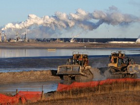 Workers use heavy machinery in the tailings pond at the Syncrude oil sands extraction facility near the town of Fort McMurray in Alberta.