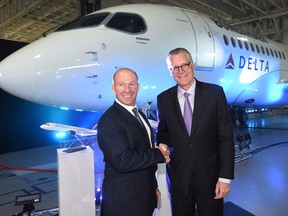 Alain Bellemare, left, president and CEO of Bombardier Inc., and Ed Bastian, right, CEO of Delta Air Lines, shake hands in front of a Delta-branded Bombardier C-Series jet in Mirabel, Que.
