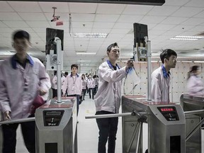 Employees look into facial recognition devices as they swipe their badges to enter the assembly line area at a Pegatron Corp. factory in Shanghai.