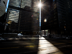 A pedestrian walks in the heart of Toronto's financial district at Bay and King streets.