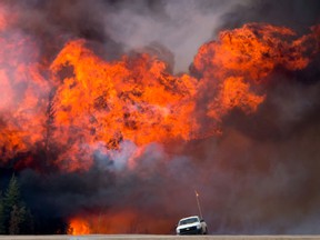 A wildfire burns behind an abandoned truck on Alberta Highway 63 near Fort McMurray, Alberta.