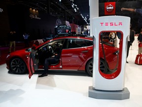 A charging plug sits attached to a Tesla Model S automobile, produced by Tesla Motors Inc., at the Paris Motor Show.