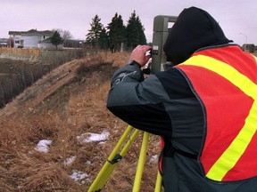 A city surveyor works to locate the property  boundries. doing a story on the papadopoulos house. It's been tbe bane of the city's existence for a decade as it's been slipping into the ravine and the subject of lawsuits. And this week nicolaos papdopoulos has been out clearing more land apparently in parkland. I want to go with the photog. We'll get sopme pics of the work and then knock on Mr. P's door....