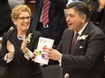Ontario Premier Kathleen Wynne applauds Minister of Finance Charles Sousa as he releases the budget at the Ontario Legislature