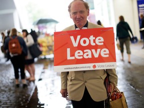 A "Vote Leave" campaigner wearing a placard around his neck distributes leaflets to members of the public in Manchester, U.K.